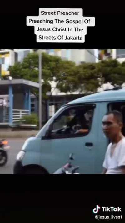 Street preacher in Jakarta preaching the gospel while people walk by ignoring him.
