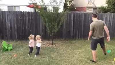 Man Teaching his daughters how to do cartwheel.