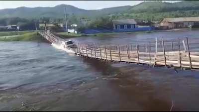 Car trying cross river during flood on a pedestrian bridge