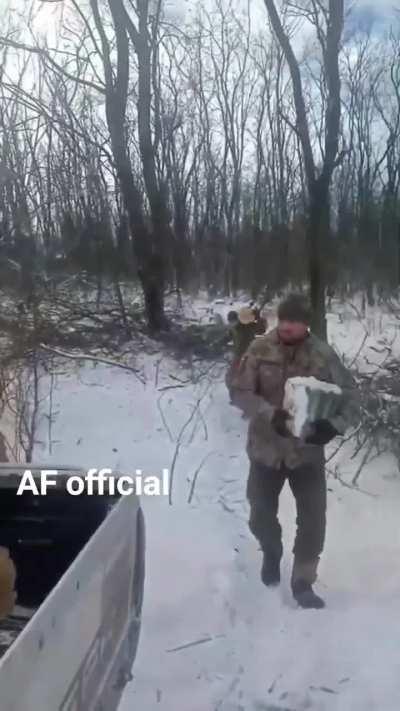 Ukrainian soldiers load up their pickup truck with firewood for winter warmth.