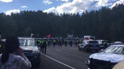 Indigenous protesters at Mount Rushmore (sacred Lakota land) have removed the tires from the large white vans in the background, creating a road block that will be very difficult to move.