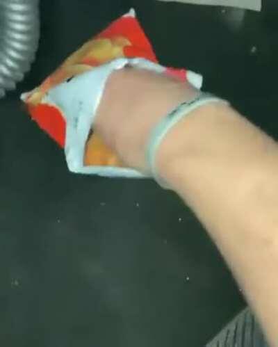 Man eats bag of chips while sitting inside a half-flooded car.