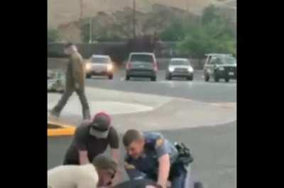 Cop brings dog over to bite pinned mans leg.