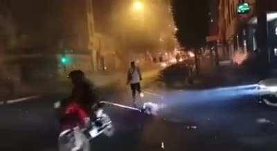 A guy makes a little jump to avoid getting hit by a chainsaw dragged by a motorcycle