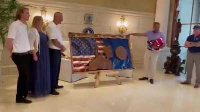 The American flag has been used as a drape to cover a “Fight Flag” depicting President Donald Trump
