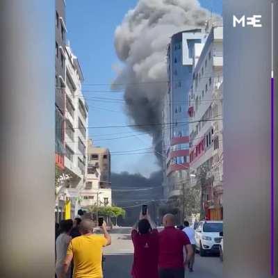 The owner of al-Jalaa tower pleads with an Israeli army officer on the phone live on TV to let journalists collect their gear before he bombs it. Moments later, Israeli air strikes demolish the building that housed several international media offices used
