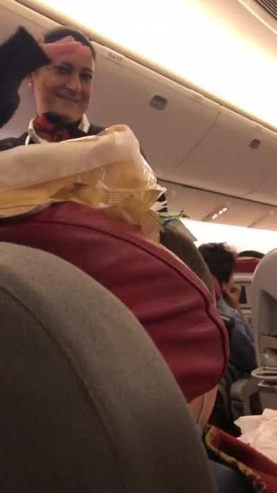 Flight attendant joins my family in stacking random stuff on my sleeping brother