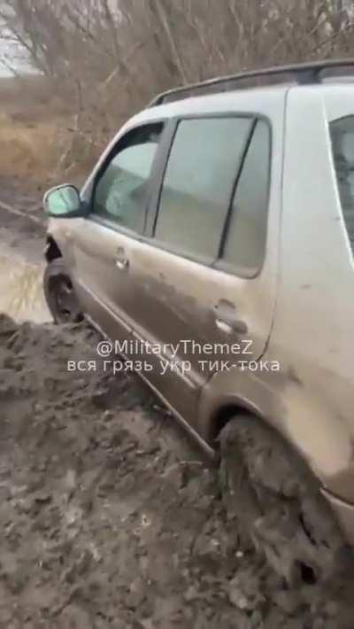 RU POV: Two Ukrainian soldiers that transported aid and ammo to frontline soldiers gots their car stuck in the mud. They also complain about how they will remove the car from the mud. Avdiivka Coke Plant can be seen on the background