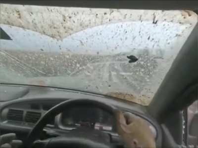 Ukrainians driving on a muddy road narrowly avoid an explosion that shatters their windows. 