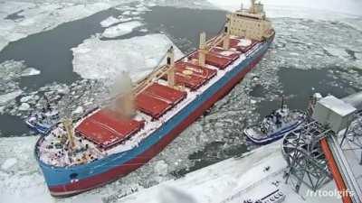 Couple of tugboats parallel park a ship