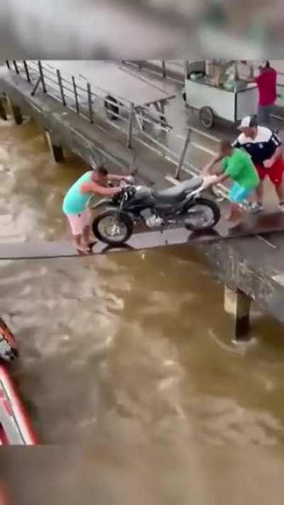 Trying to move a bike across a plank over turbulent water