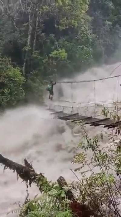 A man crossing an overflowing dangerous bridge in Anjaw District , Arunachal Pradesh
