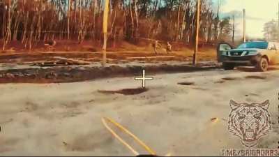 Russian fiber optic drone maneuvers around an anti-drone net and hits a pickup truck as soldiers are running away.