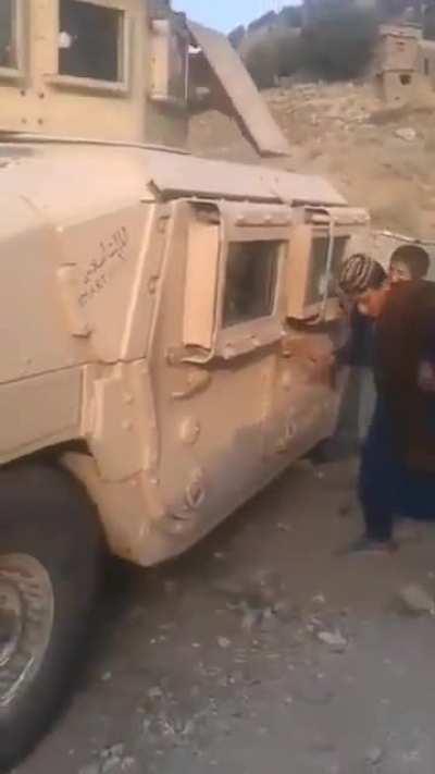 Afghan children playing with an abandoned Humvee