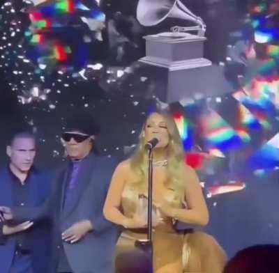 To hand Mariah Carey the microphone