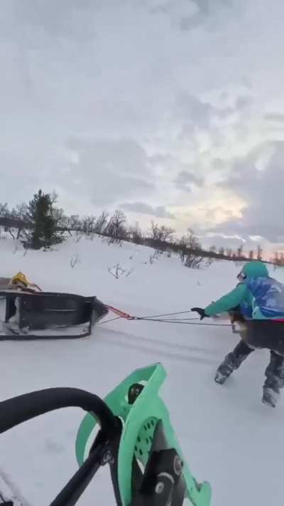 A woman saves another woman who is being dragged as she hangs onto the dogsled
