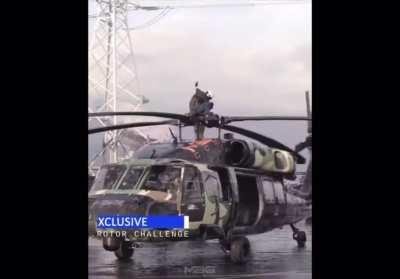Guy stands on the top of spinning helicopter rotor