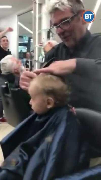 The barbers in this barber shop started singing to calm/distract this little kid, who was about to cry.