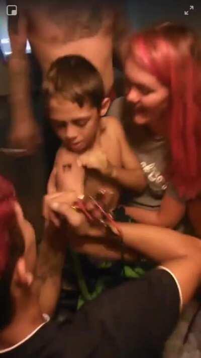 Gif format to protect the 9 year old’s name. Mother has him tatted, at her house, by an amateur without sterilized gloves or any health precautions. Also seen in the video are needles on the table. These people have been reported to every department possi