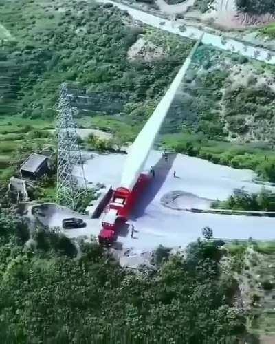 Transporting a massive turbine blade up a winding mountain road.