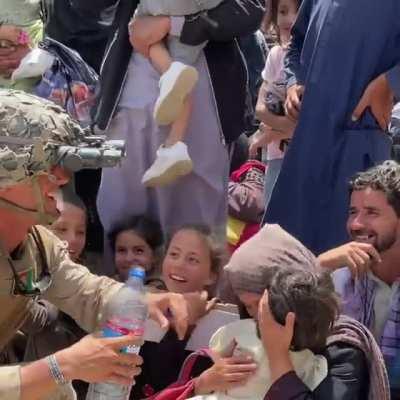 US Marine gives water to Afghan kids.