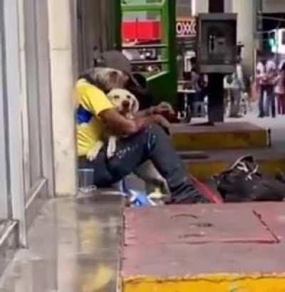 Dog approaches and hugs homeless man