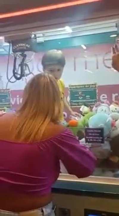 kid decided to enter a claw machine while mom wasnt looking