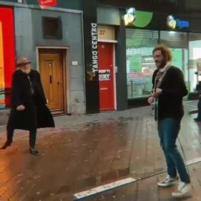 Old man vibing with a street performer