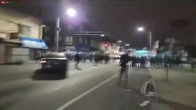 Rioters throw rocks at a car which goes down a blocked of street in Philadelphia, last night