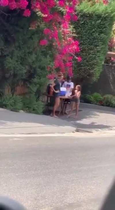 During gasoline shortage and long waiting lines, a woman and her kids are distributing water and sodas for free