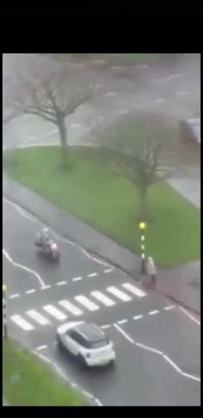 A group of bikers stop and help an old lady cross the road, whilst other road users ignore her and the rules of the road.