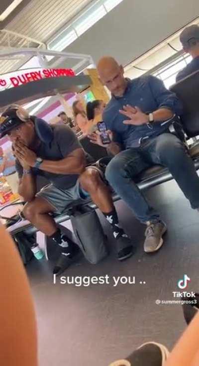 Man becomes disturbed when another person takes a seat next to him at the airport