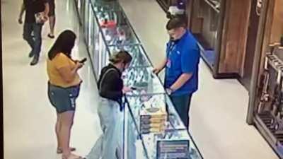 Girl points gun at friends face in gun store
