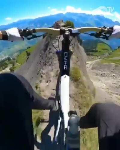 Riding a mountain bike down a ridge line.