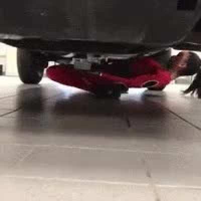 A woman does the limbo dance under a pickup truck