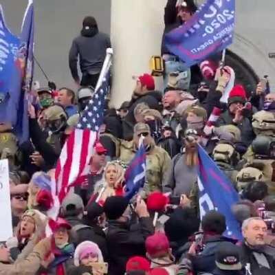 A long, disciplined line of men in body armor moves as a unit up the Capitol Building steps.