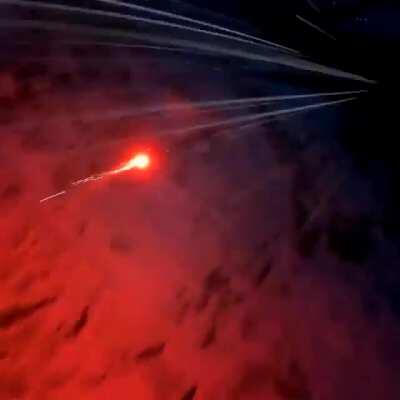 Man ties some sort of flare gun to his feet and jumps off a cliff in a wingsuit looking like a comet.