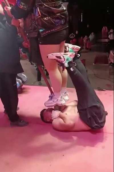 Lady standing on a shovel on a neck of a guy