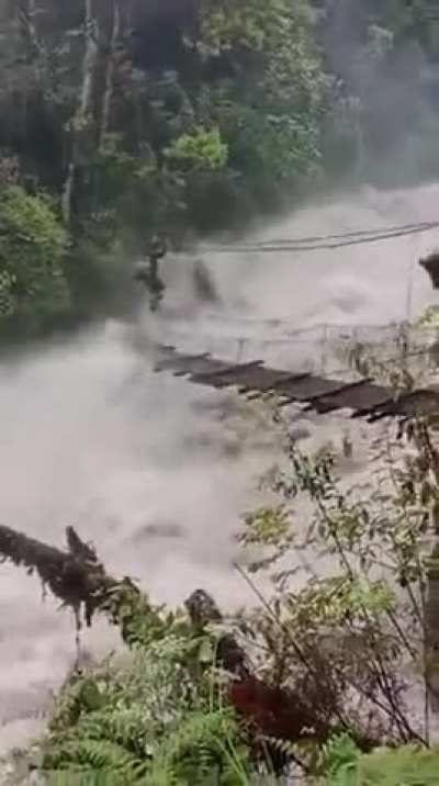 A man crossing a dangerous bridge over fast moving river