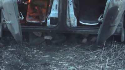Russian soldiers are hiding under a destroyed and burning infantry fighting vehicle.