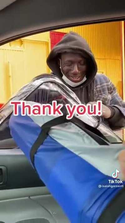 A guy helping to put a smile on a homeless mans face