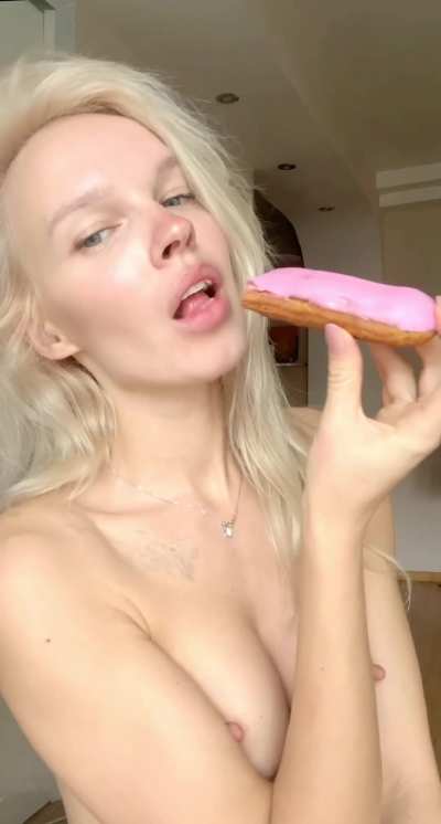 I'm super turned on, eating a pink frosted donut with my tits exposed