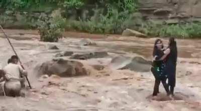 Two girls enter a flooding river to take selfies, get stuck.