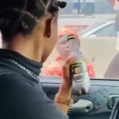 Nigerian social media influencer teasing a child beggar with a bottle of drink.