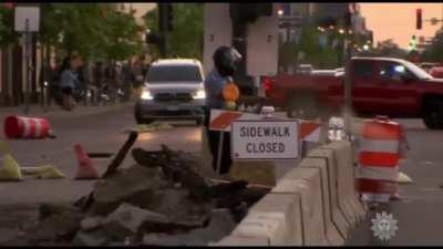 Police officer spraying pepper spray on water bottles left for protesters