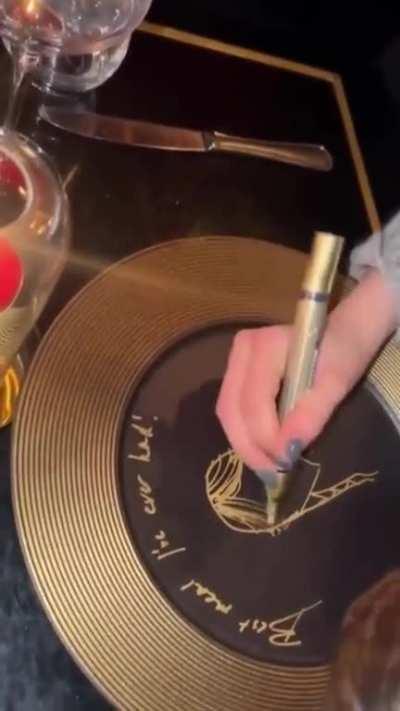 Jenna signs a plate at a restaurant in Paris