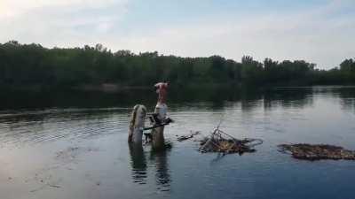 Teenager stands on top of old and abandoned boat while it sinks into lake