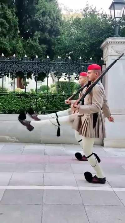 The Evzones are the Presidential Guard of Greece. An evzone must stand at least 1.87 meters tall, it’s preferable for their knees to touch as they stand upright, and they must be fit enough to raise their legs to shoulder height, completely straight, as t