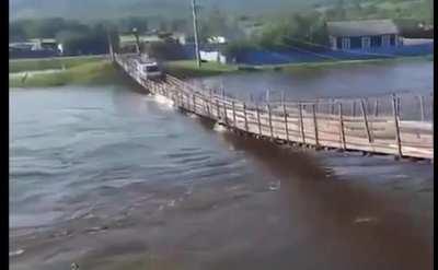 Over confident driver uses a rickety bridge that's being overtaken by a swollen river