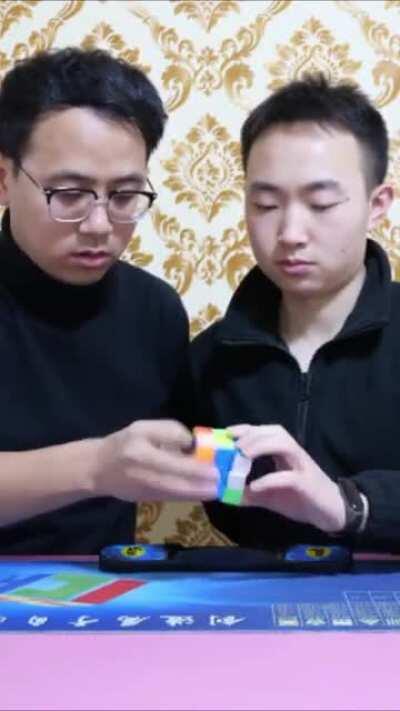 Two men (Xia Yan and Wang Penhcheng) speedcubing the same rubik's cube and break the world record (13.70 seconds)